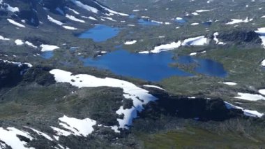 Bir gölden Jotunheimen Ulusal Parkı 'ndaki bir dağ manzarasına doğru eğil.