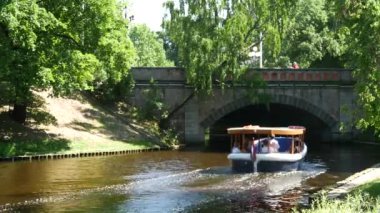 Bastion Hill Parkı Riga Letonya 'daki Pilsetas Kanalları' ndan tekne geçiyor.