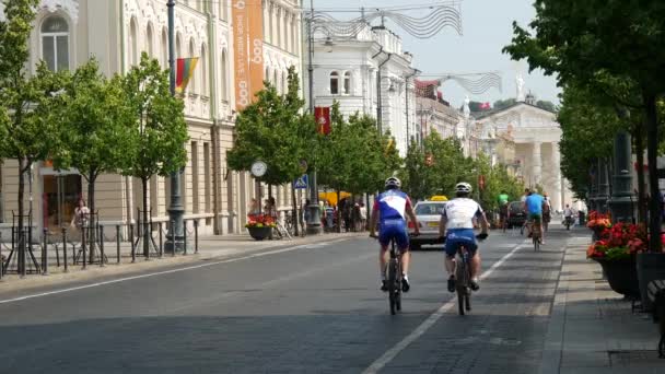 ゲディミナス アベニューでサイクリングするバイカーは リトアニアの大聖堂広場に向かってサイクリングします — ストック動画
