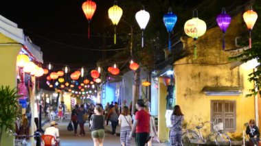 Hoi An Vietnam 'daki renkli fenerlerle dolu bir sokakta turistler.