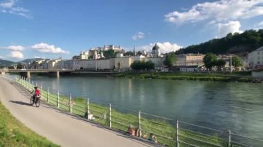 Avusturya, Salzburg 'da Salzach nehri boyunca bisiklet süren bir kadın