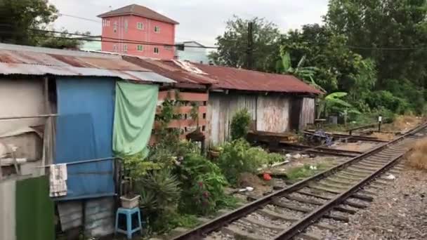 トンブリー駅を出て バンコクの鉄道の隣の家を通り過ぎるタイ — ストック動画