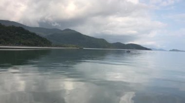 Bang Bao Körfezi 'nden küçük bir tekne ve suda yansıyan bulut görüntüsü.