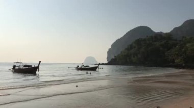 Gün batımında Koh Mook Tayland 'daki Farang Sahili' nde uzun kuyruklu tekneler.