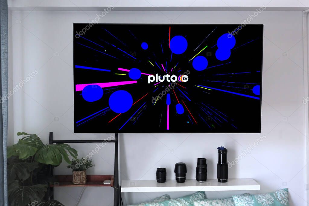 Hi, USA - May 21, 2020: Pluto TV cable service provider logo with graphic background on a home entertainment wall mounted flat screen.