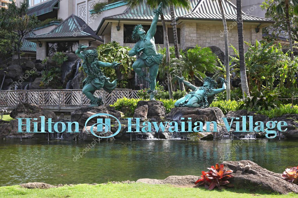 Honolulu, Hawaii - March 30, 2020: Weathered green copper statues and name sign with logo of worldwide hotel chain Hilton in Waikiki's Hawaiian village.