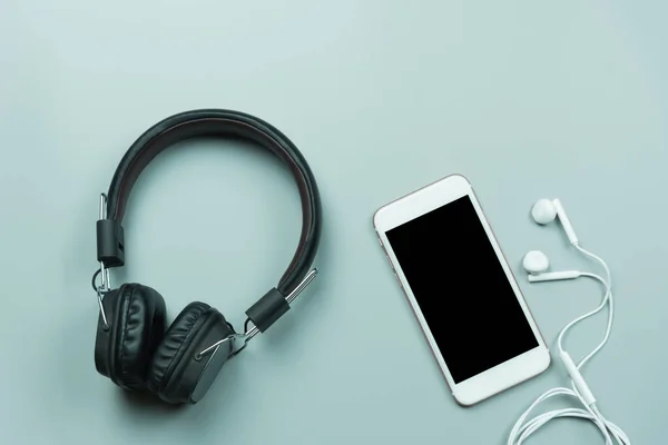 Gri arkaplanda cep telefonu ve kulaklık