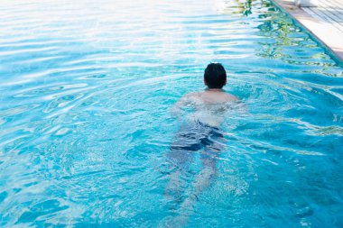 Tatil köyündeki havuzda yüzen sporcu.