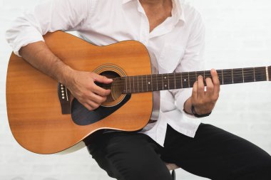 adam beyaz zemin üzerine akustik gitar çalmak