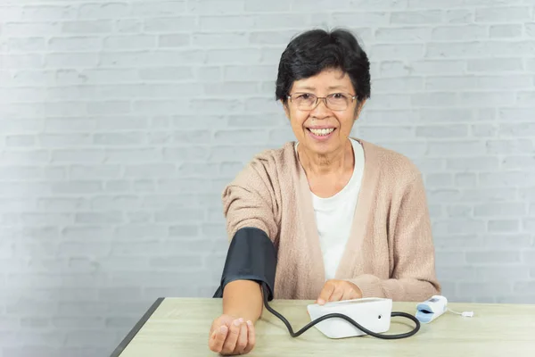 Alte Frau mit Tonometer zur Kontrolle des Blutdrucks — Stockfoto