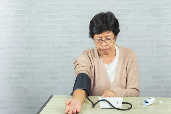 old woman with tonometer checking blood pressure level