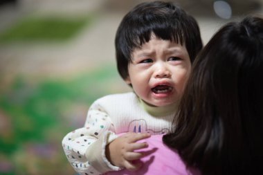 Sevimli bebek ağlıyor ve annesine sarılıyor.