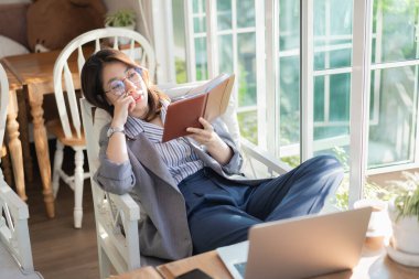 Çalışan kadınlar not defteri okuyor ve kafede çalışıyor.