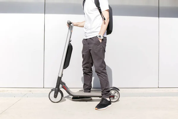 Genç adam caddenin üzerinde elektrikli scooter üzerinde rahat kıyafet