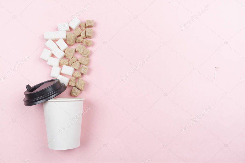 Sugar cubes in a paper Cup of coffee on a pink background