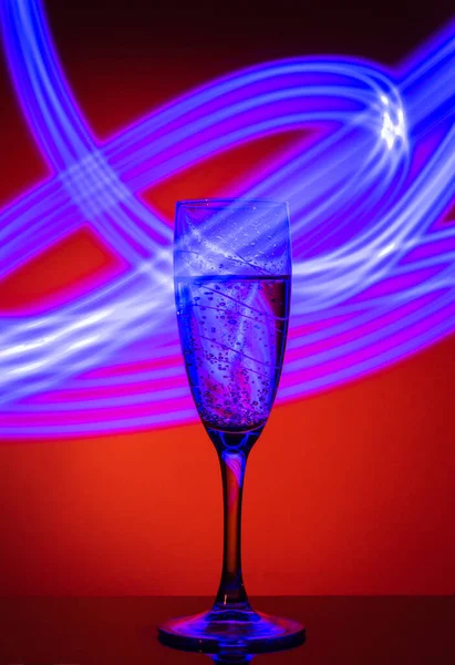 Bicchiere Champagne Sfondo Arancione Con Effetto Disegnare Luce Blu Una — Foto Stock