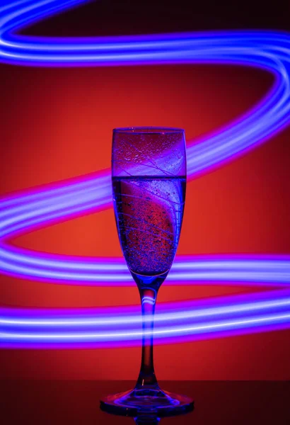 Bicchiere Champagne Sfondo Arancione Con Effetto Disegnare Luce Blu Una — Foto Stock