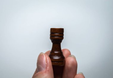 El bir satranç taşını tutar. Beyaz arkaplanda satranç kalesi