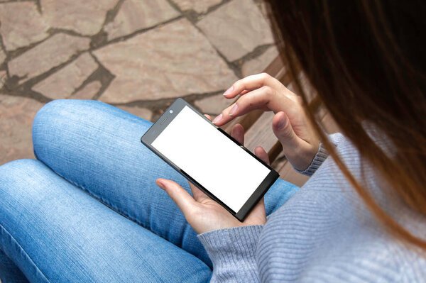 The girl is holding a smartphone. Smartphone mockup in the hands of a girl