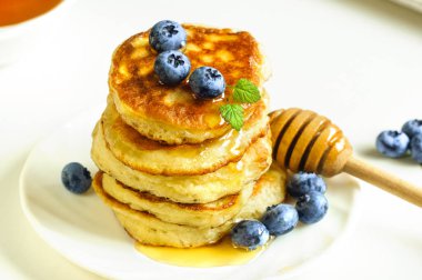 Çörekler, krepler beyaz bir tabakta yakın plan. Tatlım, yabanmersini. Seçici odak