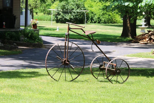 a vintage antique rusty three wheel bicycle bike trike parked on a grass lawn