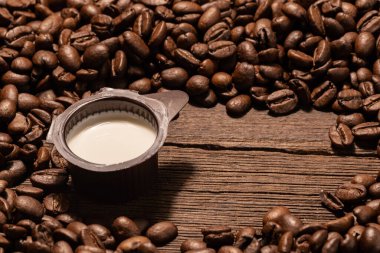 Az sütlü, kahve çekirdeğinin arka planında kremalı kahve kabı. Mono servisleri.