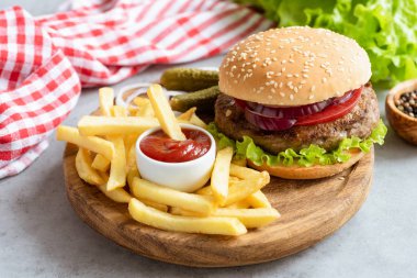 Tahtada ketçaplı ev yapımı sığır burger ve patates kızartması.