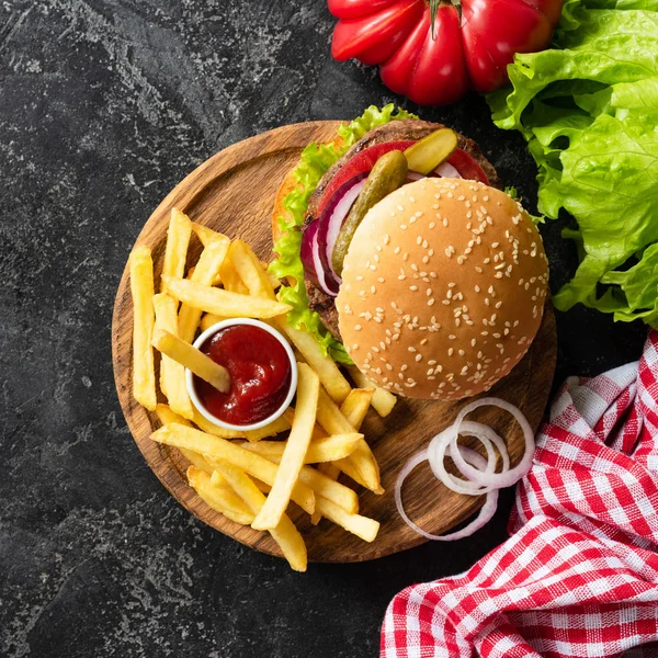 Lezzetli burger sığır eti, patates kızartması ve ketçap koyu arka plan üzerinde