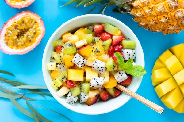 Fruit salad with tropical and exotic fruits on blue background — Stock Photo, Image