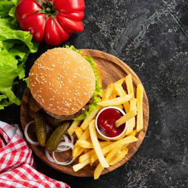 Hamburger, patates kızartması, turşu ve ketçap ahşap tahta üzerinde. Fast food