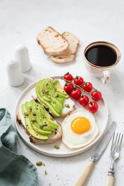 Тост с авокадо, яичницей, помидорами и кофе. Здоровый завтрак — стоковое фото