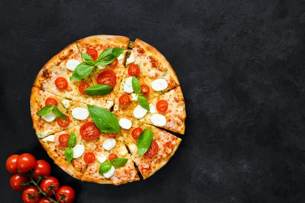 Hot italienska pizza med tomat, basilika och mozzarella på svart sten bakgrund — Stockfoto