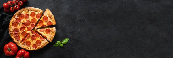 Gustosi peperoni pizza e ingredienti di cottura pomodori, spezie, basilico su fondo di cemento nero — Foto Stock