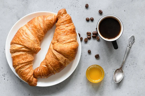 Croissants, coffee and honey on concrete background