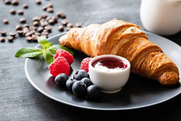 Croissant saporito, bacche e marmellata su un piatto — Foto Stock