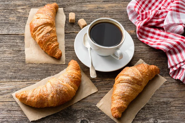 Croissant e tazzina da caffè sul tavolo di legno — Foto Stock