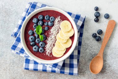 Soslar - muz, Hindistan cevizi, yaban mersini ve chia tohum ile Acai blueberry smoothie kase. Sağlıklı beslenme, sağlıklı yaşam, vegan diyet kavramı. Güler yüzlü kase üstten görünüm