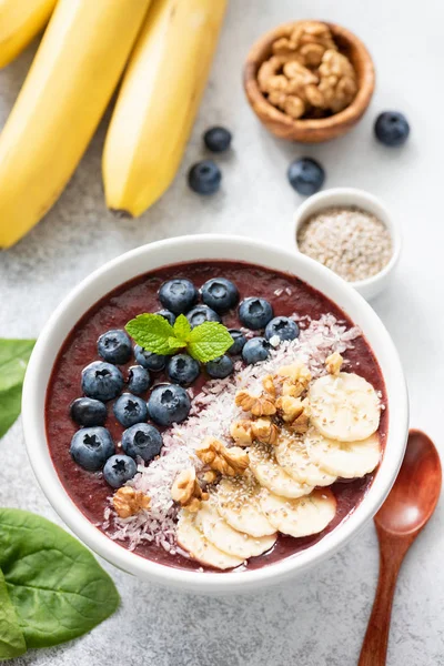 Soslar - muz, ceviz, Hindistan cevizi, yaban mersini ve chia tohum ile Acai blueberry smoothie kase. Sağlıklı beslenme, sağlıklı yaşam, vegan diyet kavramı