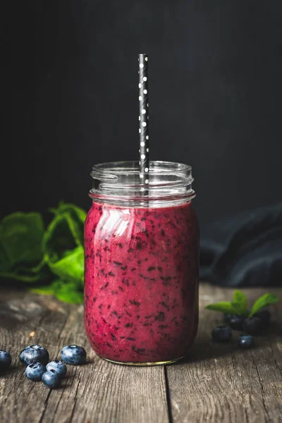 Acai smoothie şişe ahşap masa, koyu arka plan üzerinde. Seçici odak. Trendy superfood detoks vegan içki