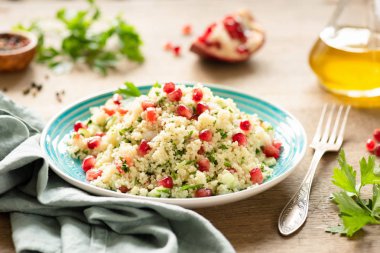 Tabbouleh, nar, maydanoz, otantik turkuaz plaka üzerinde salatalık ile Orta Doğu kuskus salatası. Vejetaryen yemek