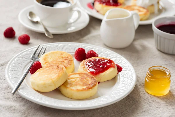 Mesa de desayuno con tortitas de requesón, miel, mermelada y café —  Fotos de Stock