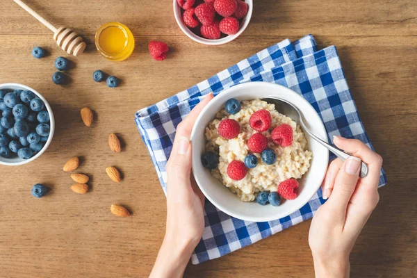 Eating healthy breakfast. Oatmeal porridge with berries in hands