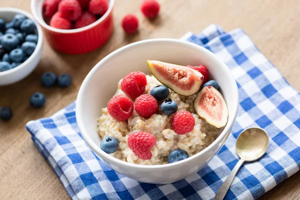 Oatmeal porridge with berries on kitchen napkin. Breakfast table — Stock Photo, Image