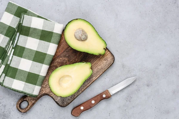 Avocado halved on wooden cutting board — Stock Photo, Image