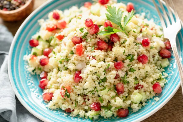 Tabbouleh salad with pomegranate seeds on turquoise plate — Stock Photo, Image