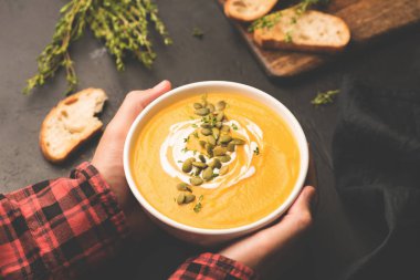 Sıcak kabak çorbası elinde tutan kişi. Konfor gıda, sonbahar gıda kavramı