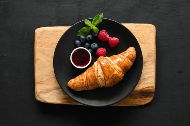 Kruvasan çilek ve siyah plaka, tablo üstten görünüm üzerinde reçel ile.