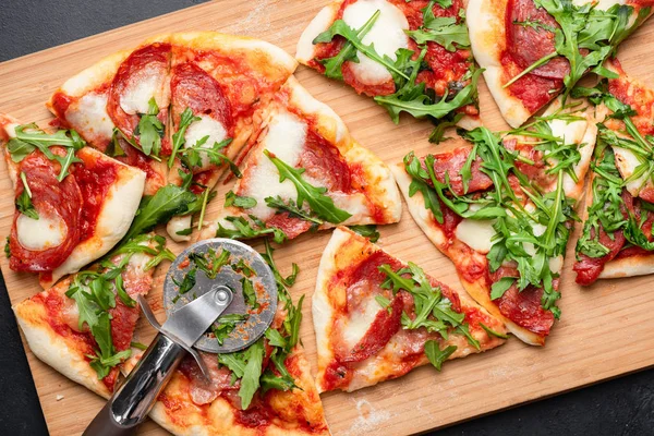 Pizza con salami, mozzarella y salsa de tomate adornada con rúcula. Pizza en rodajas —  Fotos de Stock