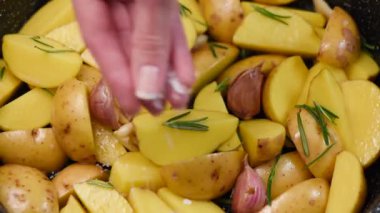Tuzlama patates dilimleri tava üzerinde. Biberiye, sarımsak, zeytinyağı ve deniz tuzu ile patates pişirme Şef. Yemek yiyecek görüntüleri