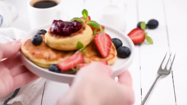在盘子里放新鲜浆果和果酱的煎饼或糖浆 把早餐盘放在桌子上 — 图库视频影像